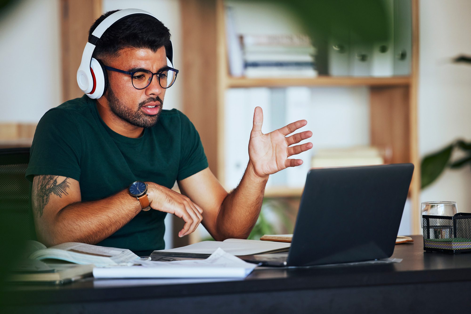 man wearing headphones looking at computer. university of dubuque online. faqs